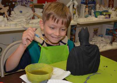 boy painting batman plaster figurine