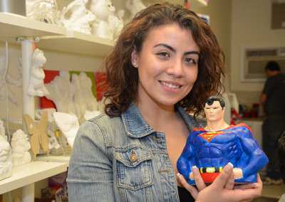 Woman painting Superman plaster figurine