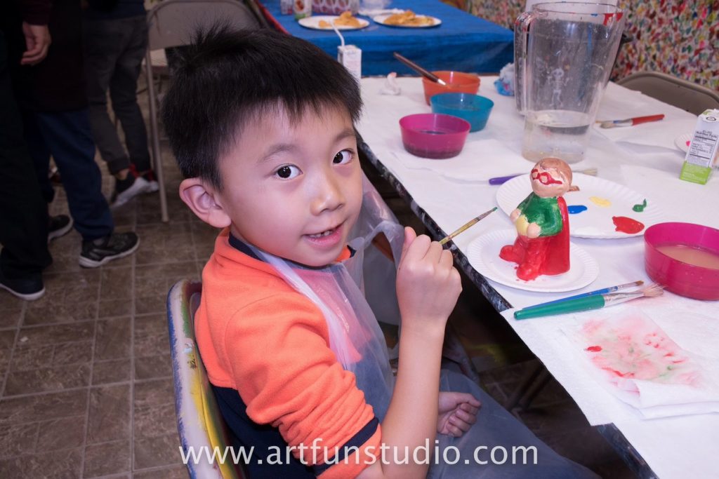 Boy painting a plaster figurine during a birthday Party