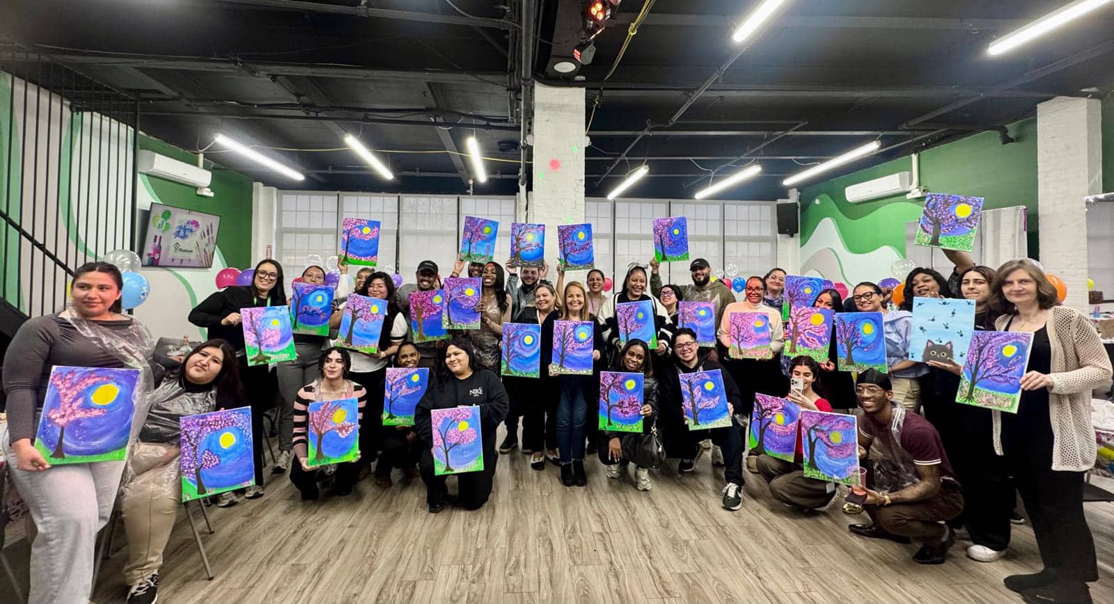Sip and paint corporate event people with artwork smiling
