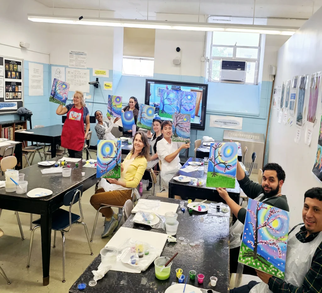 Teachers smiling and holding their artwork
